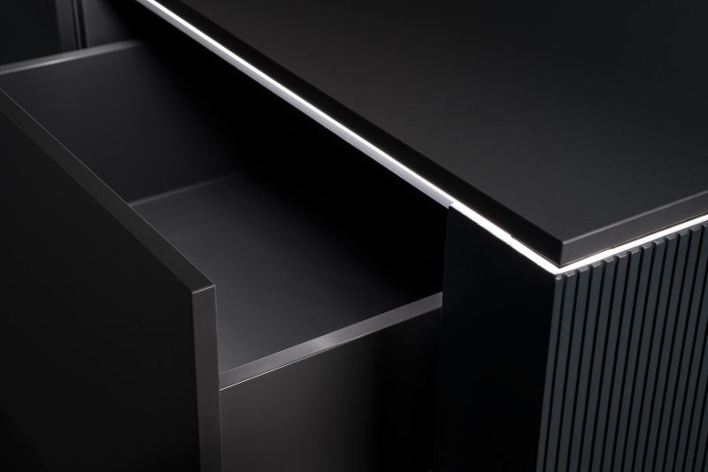 Beleuchtete Arbeitsplattenkante eines schwarzen Sideboards mit geöffnetem Fach, Lichtlinie über die volle Länge
